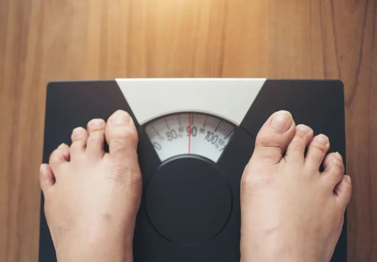 woman-feet-standing-weight-scale-wooden-background