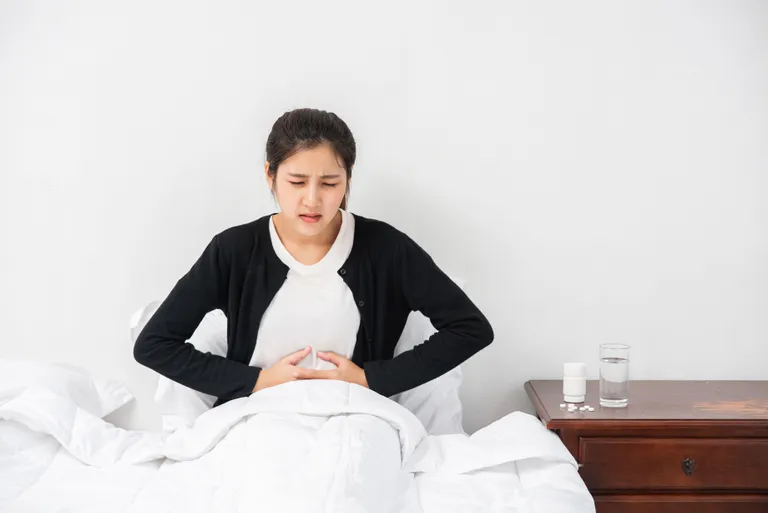 woman-sitting-bed-with-abdominal-pain-pressing-her-hand-her-stomach