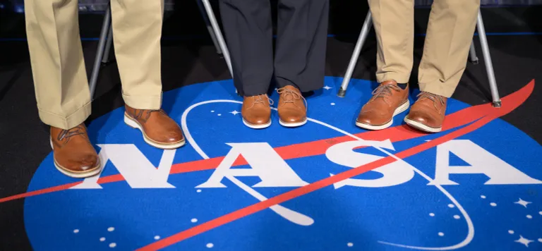 ตราสัญลักษณ์ NASA ในปัจจุบัน และเท้าของบิล เนลสัน แพม เมอรอย และบ็อบ คาบานา สามผู้บริหารหลัก