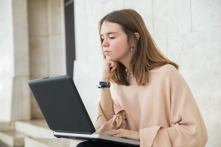 serious-female-teenager-browsing-laptop