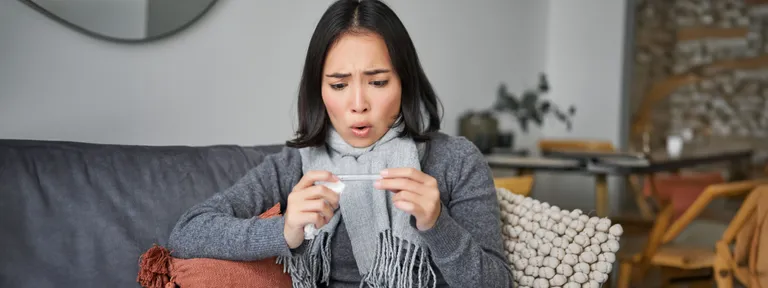 shocked-woman-looks-concerned-her-thermometer