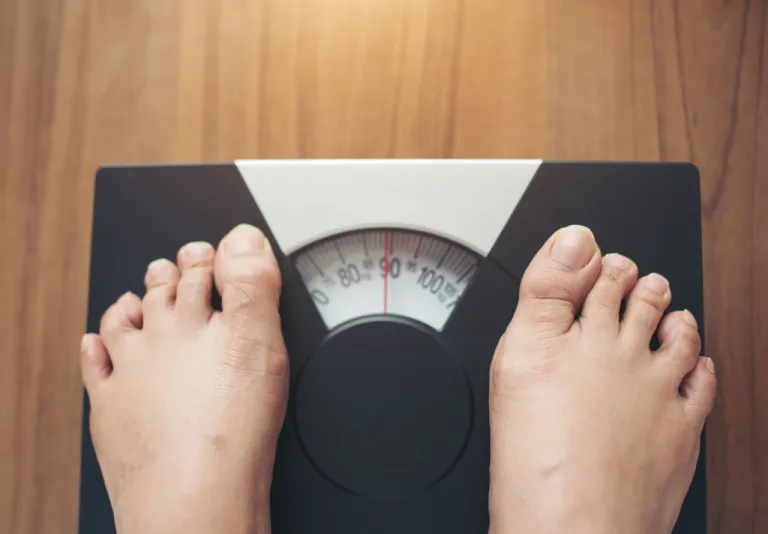 woman-feet-standing-weight-scale-wooden-background