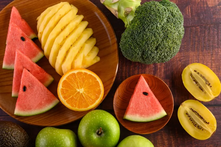 watermelon-orange-pineapple-kiwi-cut-into-slices-with-apples-broccoli-wooden-plate-wooden-table
