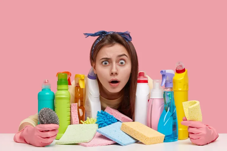 young-woman-with-unexpected-gaze-wears-headband-has-many-detergents-table-shocked-wth-dirty-room-wears-protective-gloves
