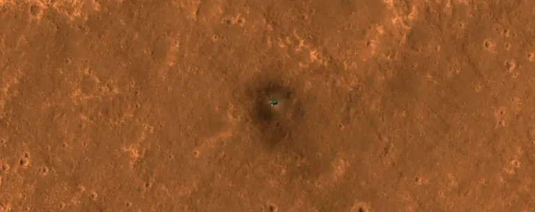 ภาพถ่ายของยาน InSight จากกล้อง HiRISE ของยาน MRO ที่ถ่ายไว้เมื่อปี 2019 จะเห็นได้ว่ายาน InSight ในเวลานั้นยังมีสีสันที่ตัดกับพื้นผิวดาวอังคารชัดเจนเพราะฝุ่นยังไม่มาเกาะบดบังแสงอาทิตย์มากนัก ภาพจาก NASA_JPL.jp