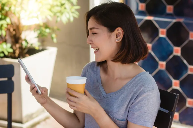 asian-young-woman-sitting-cafe-drinking-coffee-using-smartphone-talking
