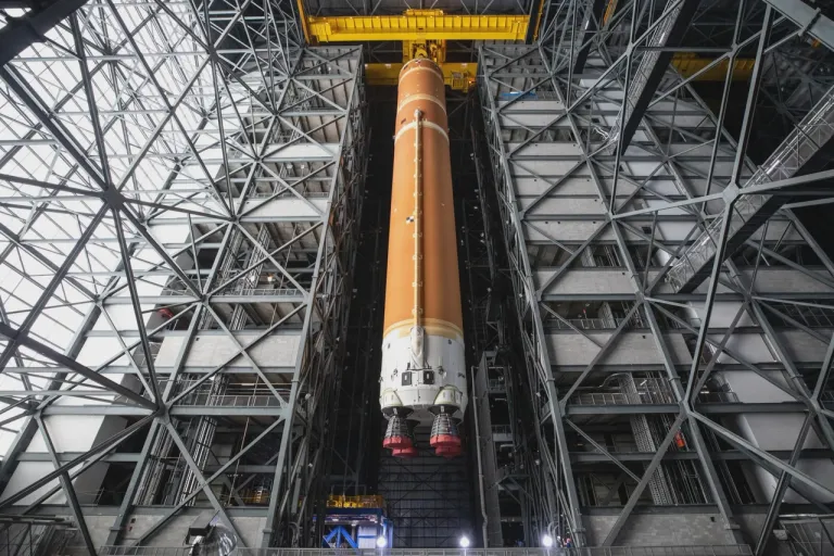 ภาพถ่ายท่อนจรวดหลักของจรวด SLS ถูกยกขึ้นด้วยเครนภายในอาคาร VAB เพื่อทำการประกอบกับชิ้นส่วนอื่นของจรวด ภาพจาก NASA