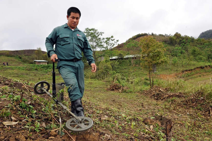 การใช้เครื่องตรวจจับโลหะค้นหาระเบิด (Photo by HOANG DINH NAM/AFP)