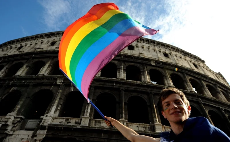 ผู้เข้าร่วมงาน EuroPride 2011 คนหนึ่งกำลังโบกธงไพรด์หน้าโคลอสเซียม (ภาพจาก: Tiziana Fabi/AFP)