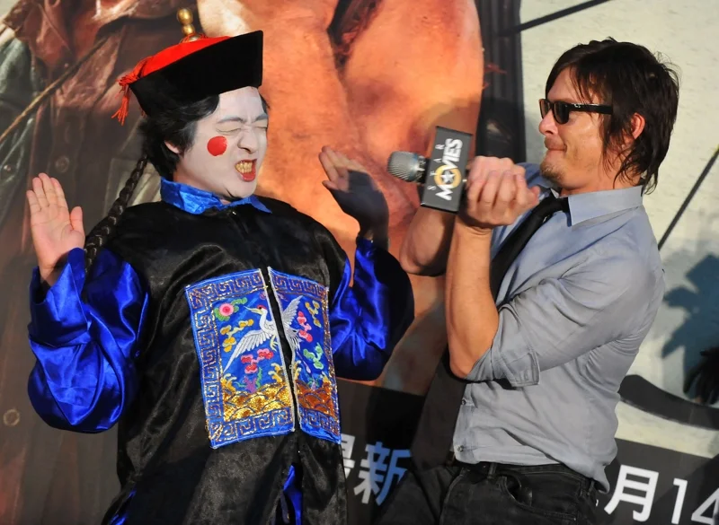 Norman Reedus (ขวา) ผู้รับบท Daryl ในซีรีส์ The Walking Dead กำลังเล่นกับแฟนคลับที่แต่งตัวเป็นซอมบี้ เมื่อปี 2013 (ภาพจาก: Mandy Cheng/AFP)